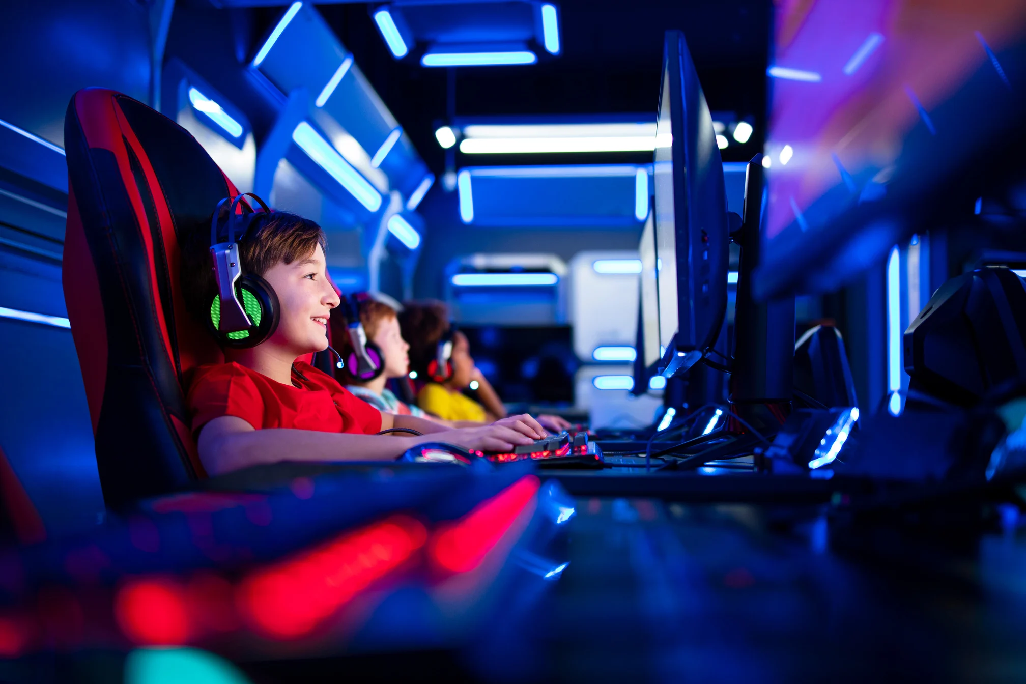 Group of children gamers playing computer video games in game room. Entertaining industry and children's addiction to video games.